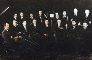 Petroskoin radiokomitean orkesteri ja perustajansa, amerikansuomalainen säveltäjä ja kapellimestari Karl Rautio (eturivissä mikrofonista vasemmalla) radion studiossa vuonna 1932. Petroskoin radiokomitean orkesteri 1932.
