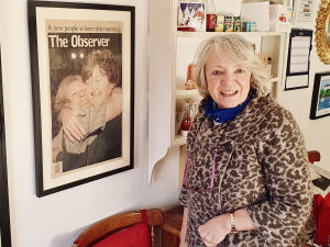 Jane Morrice i sitt kök. På planschen tidningen The Observers förstasida den 22 maj 1998, den dag nordirländarna röstade för att godkänna långfredagsavtalet. På tidningsbilden ser man en lycklig Jane krama om en annan kvinna. Jane Morrice i sitt kök. På planschen tidningen The Observers förstasida 22 maj 1998, den dag nordirländarna röstade för att godkänna långfredagsavtalet. På tidningsbilden ser man en lycklig Jane krama om en annan kvinna.
