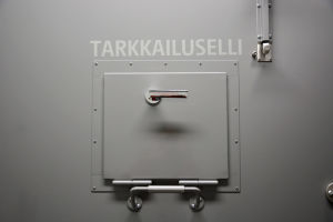 en grå dörr till en fängelsecell med lucka som är fast