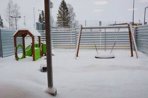 en insnöad uteplats med en gunga och en liten rutschkana i grönt