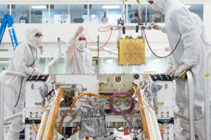 MOXIE (den guldfärgade lådan uppe på bilden) ska experimentera med att utvinna syre från Mars atmosfär. Marsrovern Perseverance i laboratoriet.