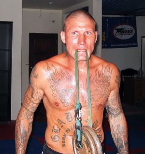 Kovaa treeniä Phuketissa 2008. Ex-thainyrkkeilijä Jarkko Stenius treenaa Phuketissa 2008. Tatuoitu mies nostaa painoa hampaillaan.