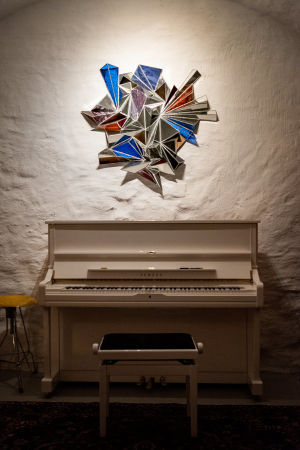 Konstverket ovanför Frida Hyvönens piano är beställt av Shala K. Friberg. Piano i källarvalv med spegelkonstverk på väggen ovanför.