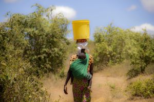 Nainen kantaa vesiastiaa päänsä päällä ja lasta selässään Kenian Nassarianin kylässä.
