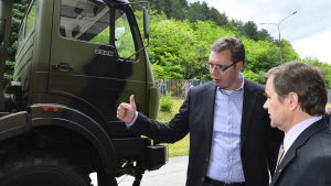 Serbiens statsminister Alexander Vucic och Sisus Timo Korhonen vid en av FAP:s speciallastbilar FAP 2228 6x6. Hytten av en militärlastbil, två män i kavaj, grön skog i bakgrunden