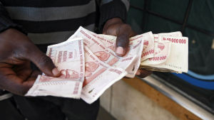 Zimbabwe frångick den egna dollarn år 2009 En man håller zimbabwiska dollarsedlar