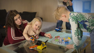 Venla och Luukas spelar Kimble tillsammans med mamma Sanja. Två barn spelar Kimble. Den ena av barnen sitter i famnen på en kvinna.