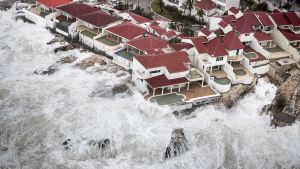 Orkanen Irma drog in över Saint Martin i fjol. Philipsburg på ön Saint Martin sett uppifrån. Vattenmassor drar in över bebyggelse.