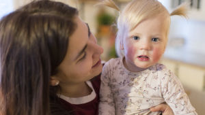 Sanja med systerdottern Bella En kvinna sitter med en liten flicka i famnen.