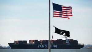 Containerfartygen blir färre i New Yorks hamn om handelskriget bryter ut. Kinesiskt fullastat continerfartyg anländer till New Yorks hamn. USA:s flagg i förgrunden.