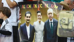 Kritiska fotbollsfans håller upp en skylt med en bild på Mesut Özil där han poserar med Turkiets president Recep Tayyip Erdogan. Kritiska fotbollsfans håller upp en skylt med en bild på Mesut Özil där han poserar med Turkiets president Recep Tayyip Erdogan.