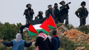 Palestinska flaggor framför israeliska soldater under demonstration i Qusra på Västbanken 30.3.2018. Palestinska flaggor framför israelisk militär under demonstration i Qusra på Västbanken 30.3.2018.