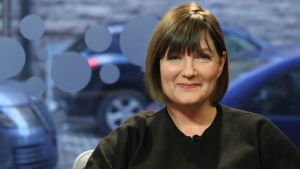 Familjetreapeuten och prästen Maria Sundblom Lindberg ler mot kameran, hon sitten framför fönstret mot gatan i Efter Nios studio.