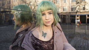 Henna har tatuerat en fjäril på sin högra axel. Hon berättar att hon egentligen äcklas av fjäriler i naturen, men på bild är de fina. Tatueringen tog hon efter att hon avslutat sitt första manus till Glasvaggan som en symbol för att hon släpper boken fri. Henna Johansdottar sitter på marken lutad mot en glasvägg medan hon tittar rakt in i kameran. Hennes jacka är uppknäppt och hon blottar en fjärilstatuering på sin högra axel.