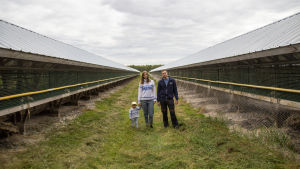 Hela familjen samlad vid Mikaels nyaste skugghus. Ett barn, en kvinna och en man står mellan två långa, låga hus. Vi befinner oss på en rävfarm.