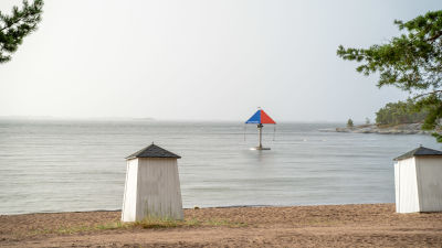 Simhus, strand, hav och en karusell i vattnet.