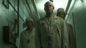 Miehet kävelevät ydinvoimalan käytävää pitkin tv-sarjassa Chernobyl. Miehet kävelevät Tsernobylin ydinvoimalan käytävällä televisiosarjassa Chernobyl.