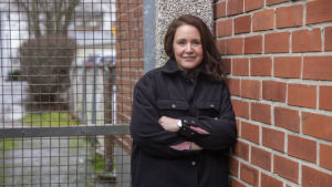Vad betyder egentligen status när det kommer till jobb? frågar sig Mikaela. En kvinna med långt hår står lutad mot en tegelvägg.