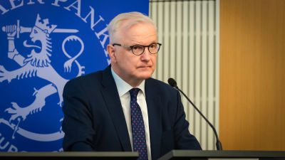 Chefen för Finlands Bank Olli Rehn står och talar framför en mikrofon.
