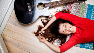 Artisten och skådespelaren Susanne Marins var med i musikalen Gambämark. Susanne Marins på golvet med en gitarr.