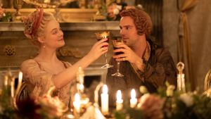 Elle Fanning och Nicholas Hoult spelar Katarina den stora och tsaren Peter den III. Katarina den stora och Peter den III skålar med vinglas i ett guldbelagt rum med tända ljus.