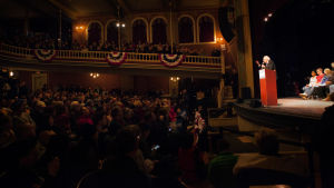 Bernie Sanders talar för sin publik på en teaterscen i Rochester, New Hampshire. Bernie Sanders står bakom ett podium på en scen framför en fullsatt publik.
