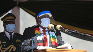 President Mnangagwa beskyller både oppositionen och USA för att försöka störta honom från makten. En man med mask och visir håller tal.