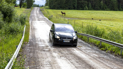 Auto ajaa kuoppaista soratietä.