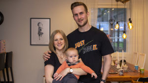 Hanna, Jani och Sagah fick en mer komplicerad start på det nya familjelivet än de skulle ha önskat. En kvinna och en man håller om varandra. Kvinnan har en bebis i famnen. De står i sitt vardagsrum.