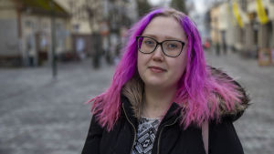 Julia Sundqvist föddes med en underutvecklad vänsterkammare. En kvinna med rosa hår och svart jacka. Går på en gågata i Jakobstad.