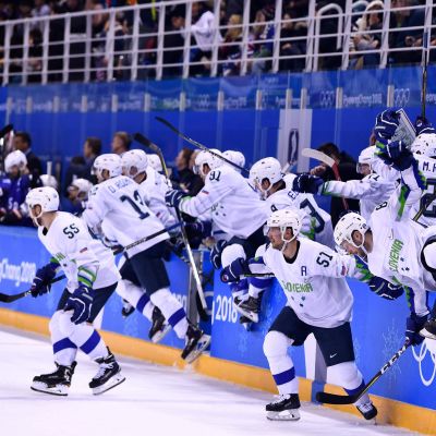 Sloveniens hockeylandslag rusar ut ur spelarbåset för att fira seger.