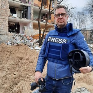 Antti Kuronen seisoo pommitetun omakotitalon raunioilla Kiovassa.