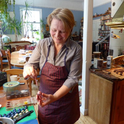 En kvinna dekormålar enchokladbit, en pralin i ett vanligt kök (hemma).