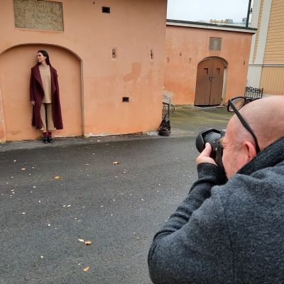 En fotograf tar foto på en kvinna som poserar med en jacka