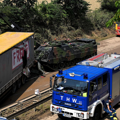 En blå lastbil och en pansarvagn bredvid en skadad lastbilskärra med texten Freja på sidan.