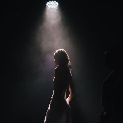 en kvinna står på scenen i strålkastarljus