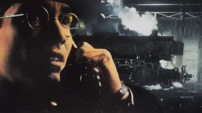 Närbild på en glasögonprydd Jean-Marc Barr stående framför ett tåg i filmen Europa.