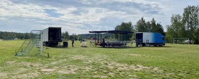 Personer håller på med att bygga upp en scen på en fotbollsplan.