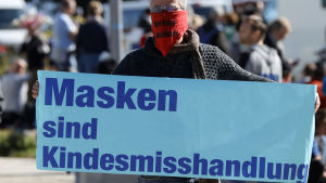 "Munskydd är barnmisshandel" lyder budskapet på den här tyska mannens banderoll. En tysk man bär en skylt där det står "munskydd är barnmisshandel" under en demonstration mot coronarestriktioner i början av oktober 2020