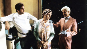 Terry Jones (i mitten) gjorde ofta kvinnliga roller i Monty Python. De två övriga är Python-kollegerna John Cleese (till vänster) och Eric Idle (till höger). Bilden är från Monty Python's The Meaning of Life från år 1983. Scen ur Monty Python The Meaning of Life. Terry Jones i mitten med papiljotter i håret. John Cleese till vänster och Eric Idle till höger.