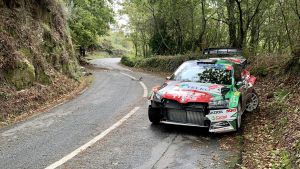 Bilen repareras som bäst på teamets verkstad i Tjeckien. En tilltufsad rallybil står vid vägkanten.