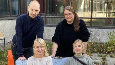 En man och tre kvinnor sitter på en bänk utomhus.