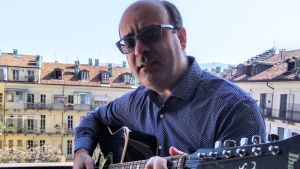 Petra Ingvesbacks man spelar gitarr på balkongen i Turin. Petra Ingvesback man spelar gitarr på balkongen.