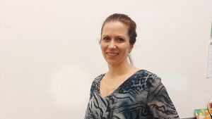 Katja Wide tycker att det är bra att barnen har valmöjligheter när det kommer till främmande språk. Leende kvinna med brunt uppsatt hår. Står framför en skoltavla i ett klassrum.