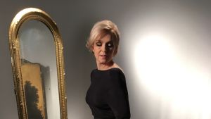 Anu Sinisalo har tagit in Marilyn Monroe i sin kropp och i sin själ. Anu Sinisalo som Marilyn Monroe i svart klänning framför en spegel.