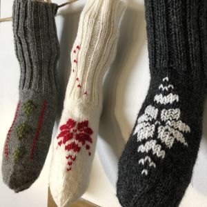 Kolme neulottuja ja kirjoitettuna sukkia roikkuu nyörillä
