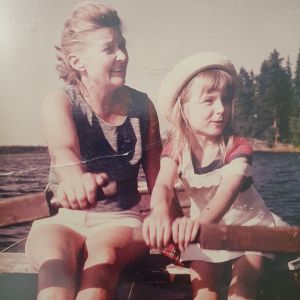 Isoäiti ja tyttö soutavat järvellä. Tytöllä on hellehattu.