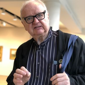 Claus Mueller, journalist och professor. Professor Claus Mueller i blåradig skjorta och axelremsväska på Sotheby´s.