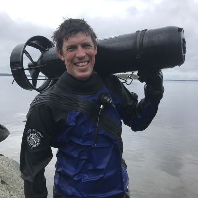 Dykaren Edd Stockdale vid en klippa. Han ler mot kameran.