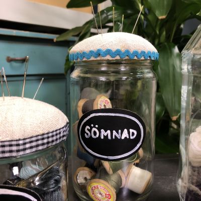 Burk med texten sömnad fylld med trådrullar